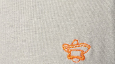 Vídeo macro del bordado en naranja flúor de la camiseta Class blanca de Knockout Couture, se aprecian los hilos y el algodón orgánico